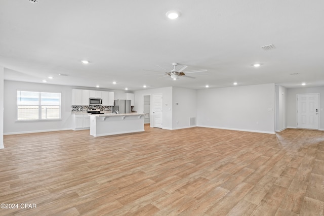 unfurnished living room featuring light wood-type flooring and ceiling fan