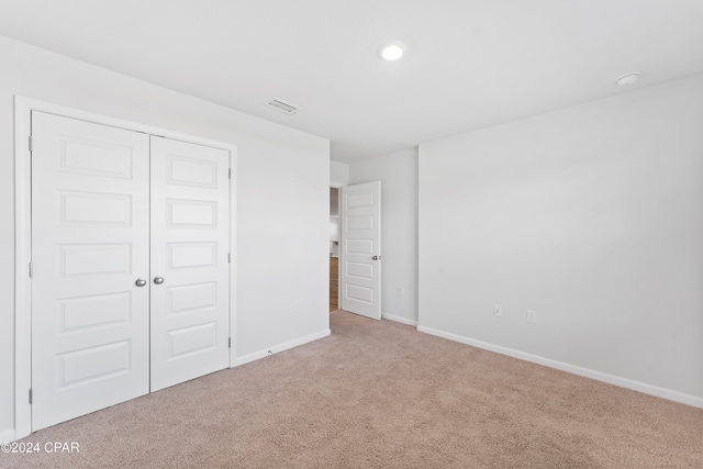 unfurnished bedroom with a closet and light colored carpet