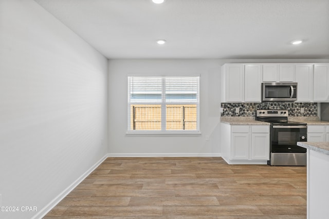 kitchen with white cabinetry, stainless steel appliances, tasteful backsplash, and light wood-type flooring