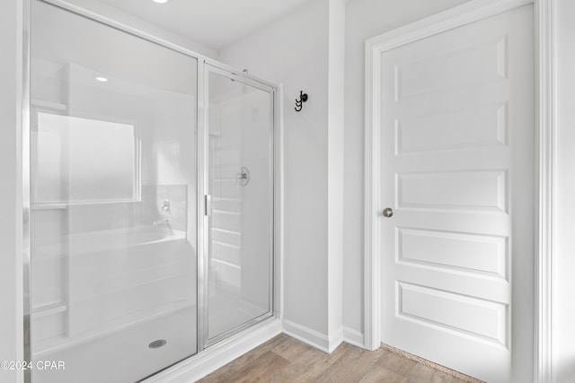 bathroom with wood-type flooring and a shower with shower door