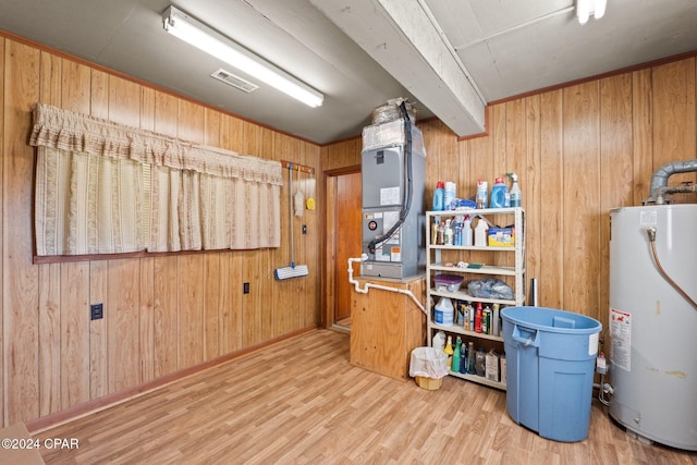 interior space with wood walls, heating unit, gas water heater, and hardwood / wood-style floors