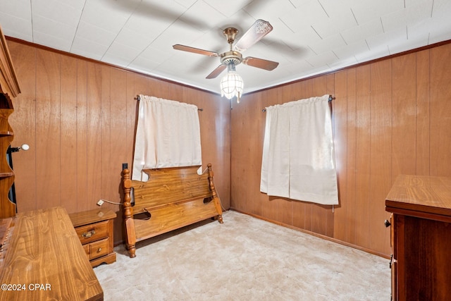 bedroom with wooden walls, light colored carpet, and ceiling fan