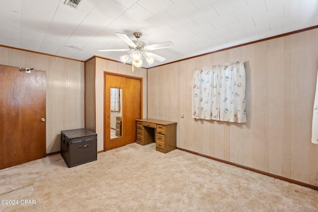 bedroom with crown molding, wood walls, carpet, and ceiling fan