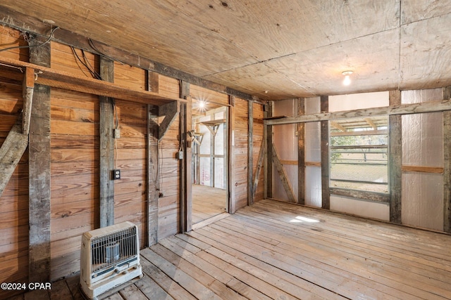 miscellaneous room featuring hardwood / wood-style floors, wooden walls, and heating unit