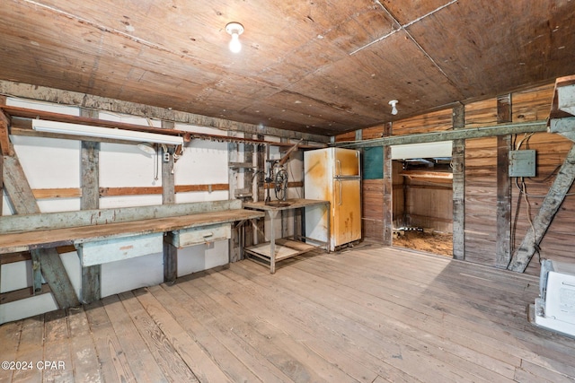 basement with wooden ceiling, light hardwood / wood-style flooring, wooden walls, and fridge