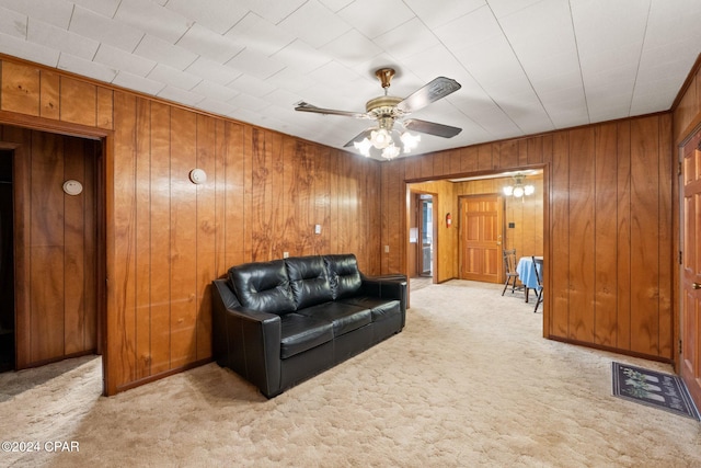 living room with light carpet, wood walls, and ceiling fan