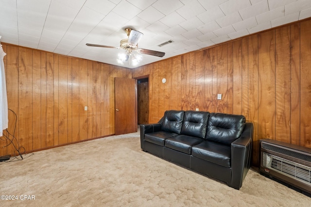 carpeted home theater room featuring ceiling fan, wood walls, and heating unit