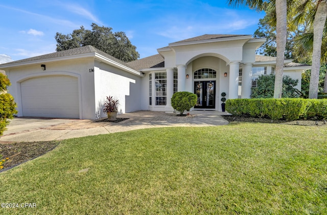 view of front of house featuring french doors, a front yard, and a garage