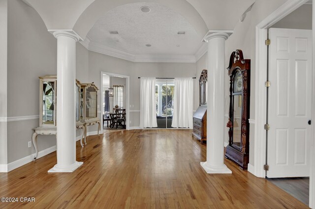 foyer entrance with ornamental molding, hardwood / wood-style floors, a textured ceiling, and decorative columns