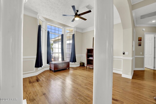 interior space with a textured ceiling, hardwood / wood-style floors, crown molding, and ceiling fan