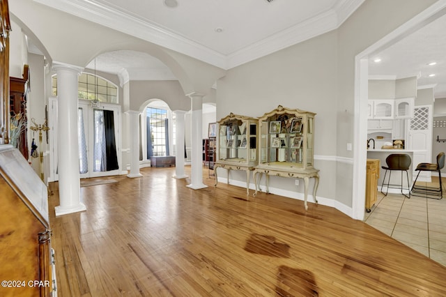 foyer with crown molding, light hardwood / wood-style flooring, and decorative columns