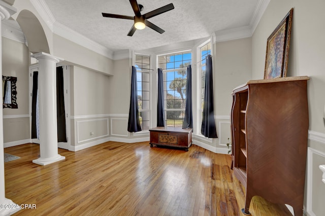 interior space featuring hardwood / wood-style floors, decorative columns, crown molding, and a textured ceiling