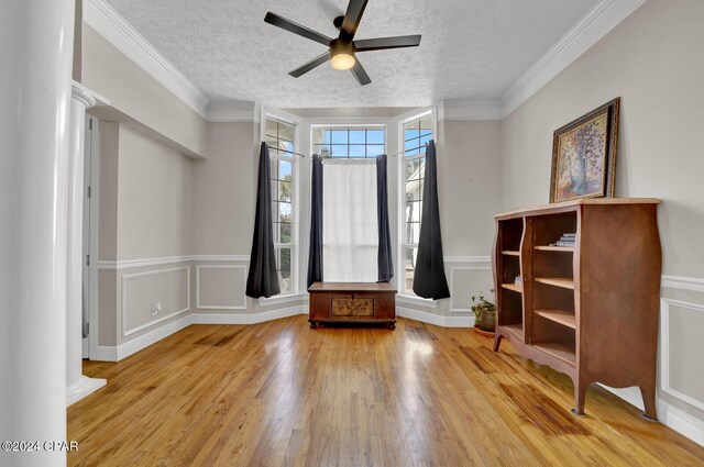 interior space with ornamental molding, ornate columns, ceiling fan, a textured ceiling, and hardwood / wood-style floors