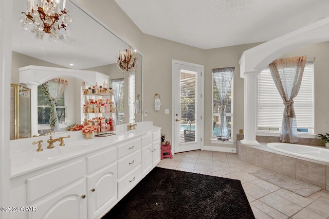 bathroom with vanity, a relaxing tiled tub, ornate columns, and a wealth of natural light