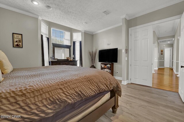 bedroom featuring light hardwood / wood-style floors, crown molding, a textured ceiling, and a closet