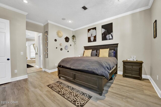 bedroom featuring ornamental molding, a textured ceiling, and light hardwood / wood-style floors