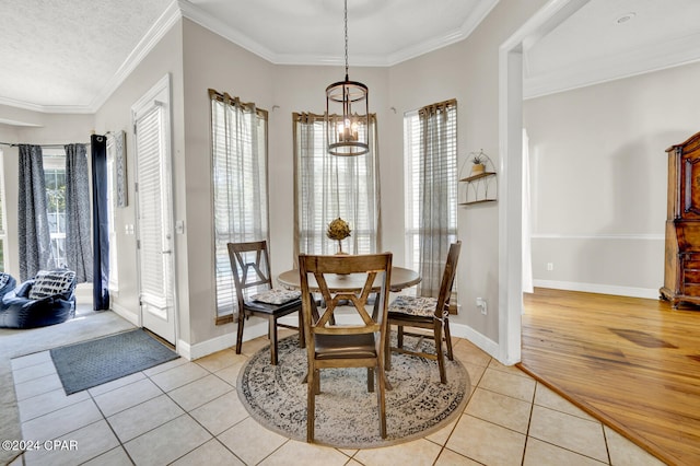 dining area featuring a notable chandelier, ornamental molding, a healthy amount of sunlight, and light wood-type flooring