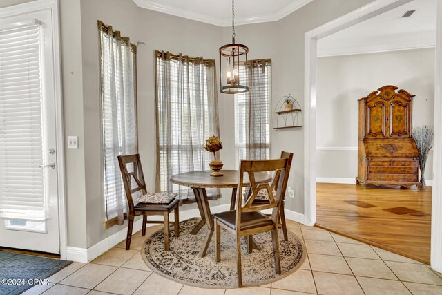 dining space featuring an inviting chandelier, ornamental molding, and light hardwood / wood-style floors