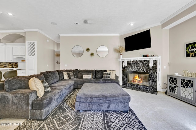 carpeted living room featuring ornamental molding, a textured ceiling, and a high end fireplace