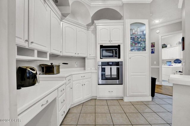 kitchen with ornamental molding, white cabinets, and oven