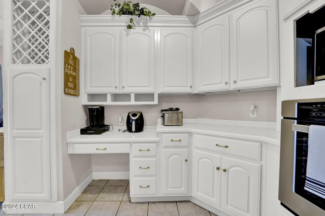 kitchen with lofted ceiling, white cabinets, light tile patterned floors, and oven