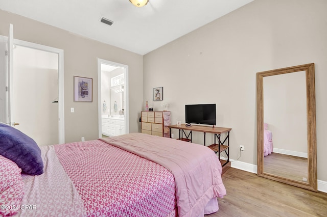 bedroom with ensuite bathroom and light wood-type flooring