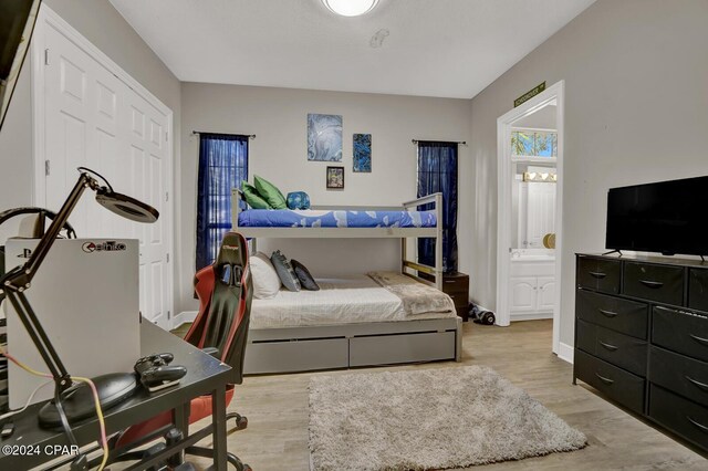 bedroom with connected bathroom and light wood-type flooring