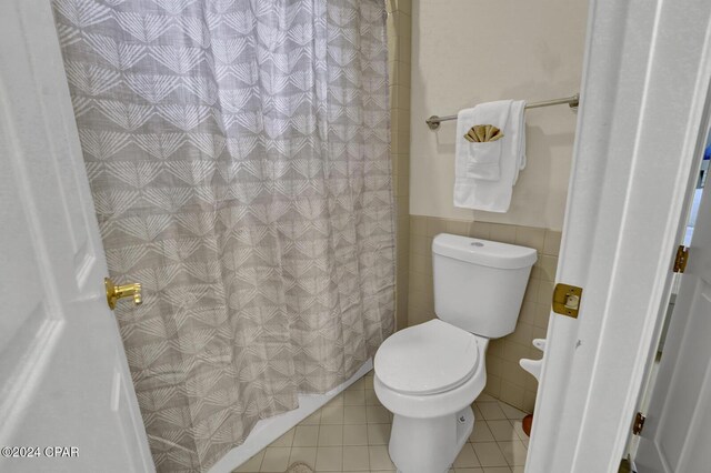 bathroom with toilet, tile patterned floors, tile walls, and a shower with curtain