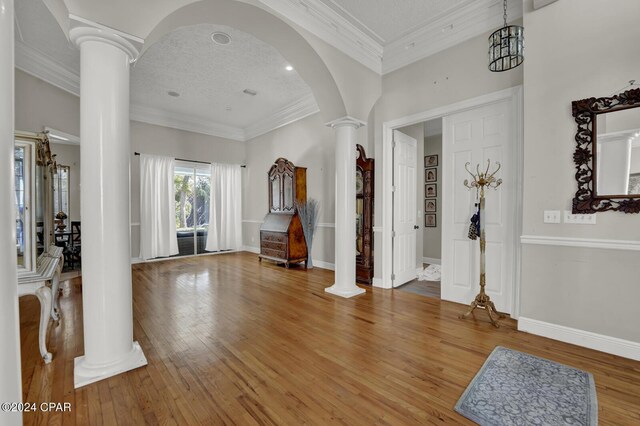 entrance foyer featuring hardwood / wood-style floors, crown molding, a textured ceiling, and decorative columns