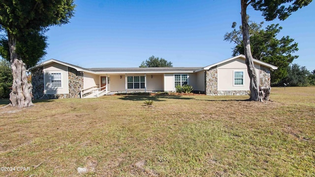 single story home featuring a front lawn and stone siding