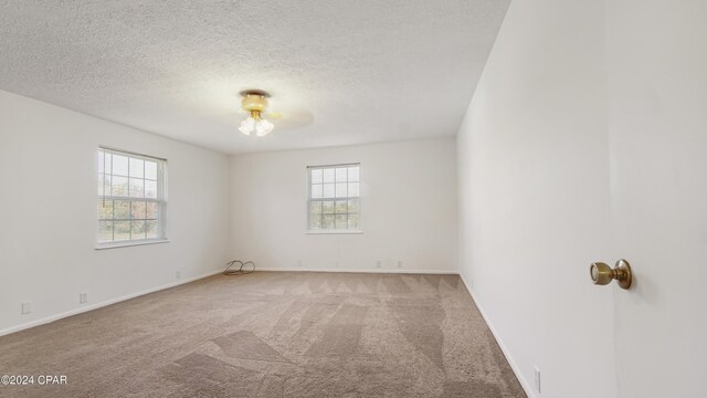 unfurnished room featuring baseboards, a textured ceiling, and carpet flooring