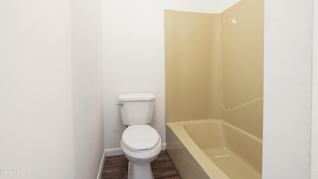 bathroom featuring baseboards, toilet, wood finished floors, a bath, and a shower