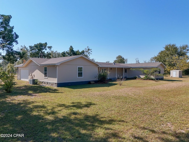 rear view of house featuring cooling unit, a lawn, a garage, and a shed