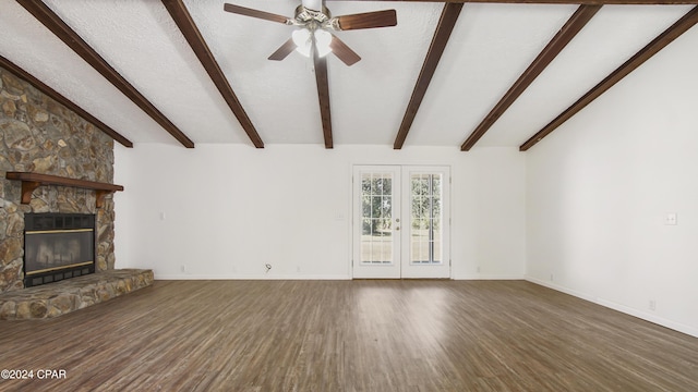 unfurnished living room with a textured ceiling, wood finished floors, a stone fireplace, baseboards, and ceiling fan