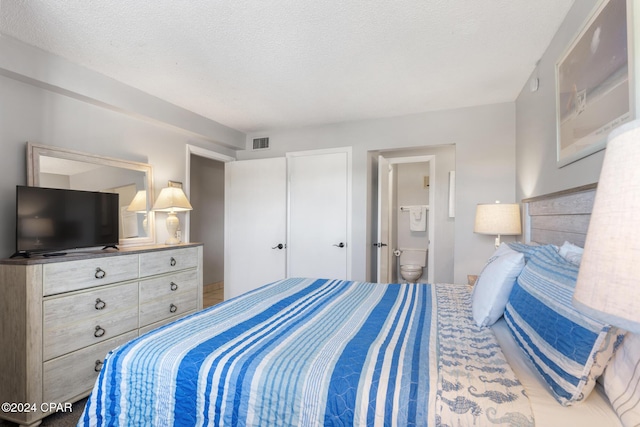 bedroom featuring ensuite bath, visible vents, and a textured ceiling