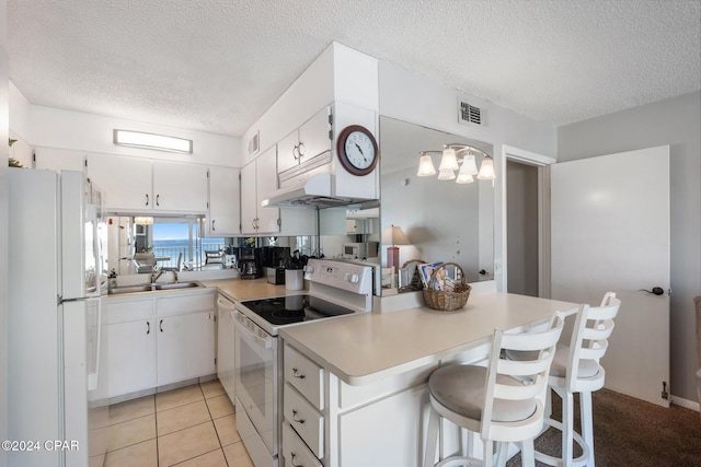 kitchen featuring a breakfast bar, white appliances, light countertops, and white cabinets