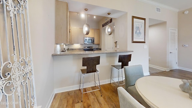 8700 Front Beach Rd Unit 5309, Panama City Beach, FL 32407 - kitchen featuring a kitchen breakfast bar, visible vents, light brown cabinets, stainless steel appliances, and wood finished floors