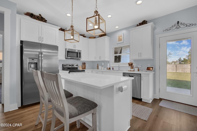 kitchen featuring white cabinets, dark hardwood / wood-style flooring, a kitchen island, stainless steel appliances, and decorative light fixtures