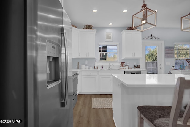 kitchen featuring appliances with stainless steel finishes, white cabinetry, pendant lighting, and wood-type flooring