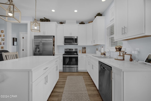 kitchen with hanging light fixtures, a kitchen island, appliances with stainless steel finishes, white cabinetry, and dark wood-type flooring