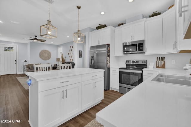 kitchen featuring hanging light fixtures, a kitchen island, appliances with stainless steel finishes, white cabinetry, and dark hardwood / wood-style floors