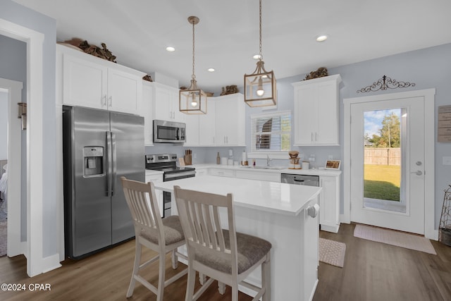 kitchen with appliances with stainless steel finishes, a center island, pendant lighting, white cabinets, and dark wood-type flooring