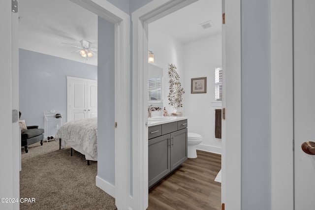 bathroom featuring vanity, toilet, hardwood / wood-style flooring, and ceiling fan