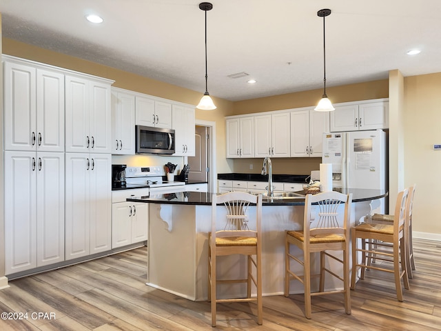 kitchen featuring an island with sink, white cabinetry, and white appliances