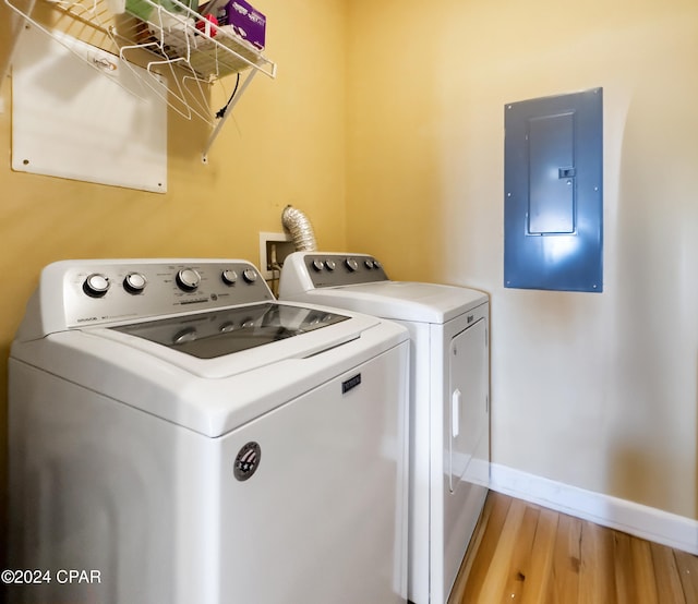 washroom with separate washer and dryer, electric panel, and light wood-type flooring