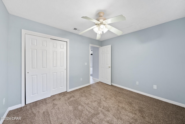 unfurnished bedroom with a textured ceiling, carpet, ceiling fan, and a closet