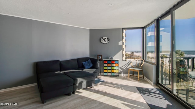 living room featuring floor to ceiling windows, hardwood / wood-style floors, a textured ceiling, and a water view