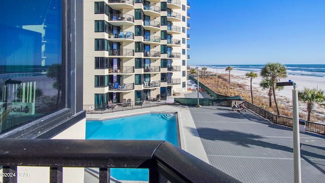 view of pool featuring a water view and a beach view