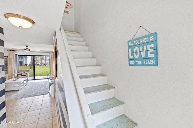 stairway featuring tile patterned flooring and ceiling fan