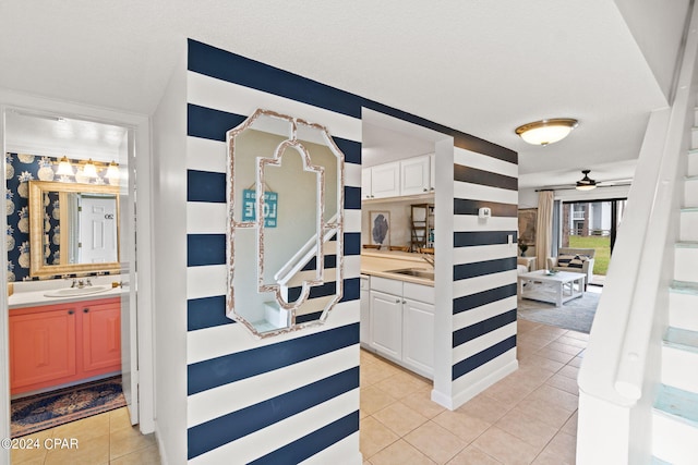 interior space with white cabinets, light tile patterned flooring, ceiling fan, and sink